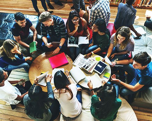 Viele Studenten lernen gemeinsam an zwei Tischen.